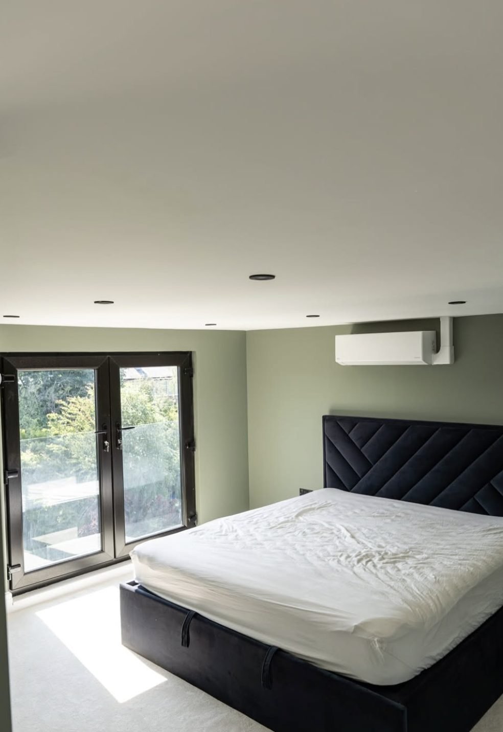 Loft bedroom with black French doors onto a Juliet balcony
