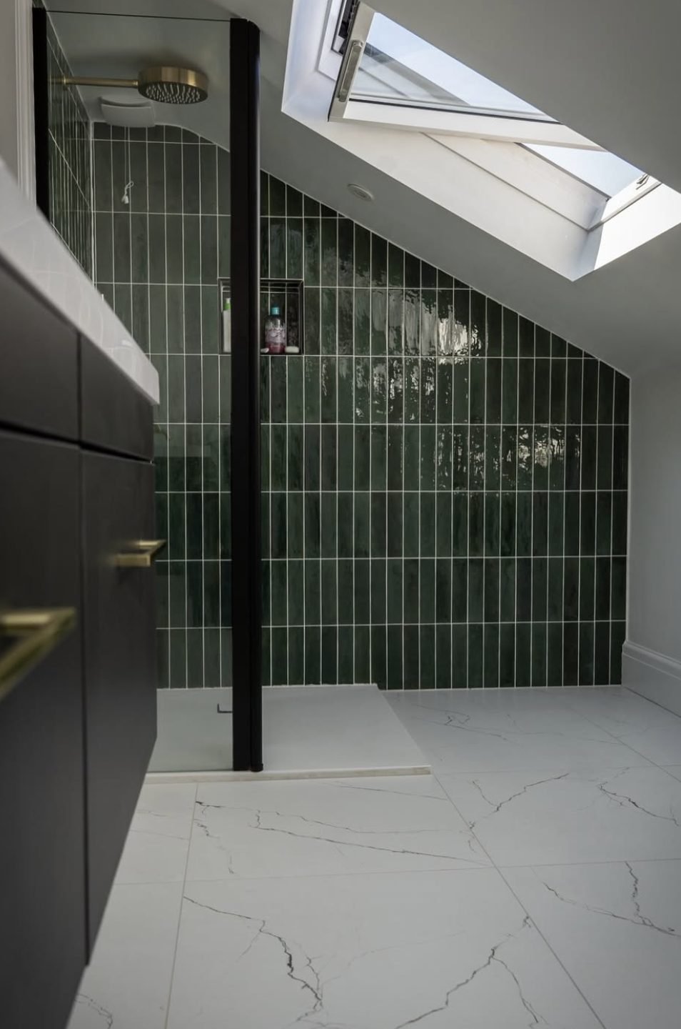 Loft ensuite with green vertical tiles and brass rainfall shower