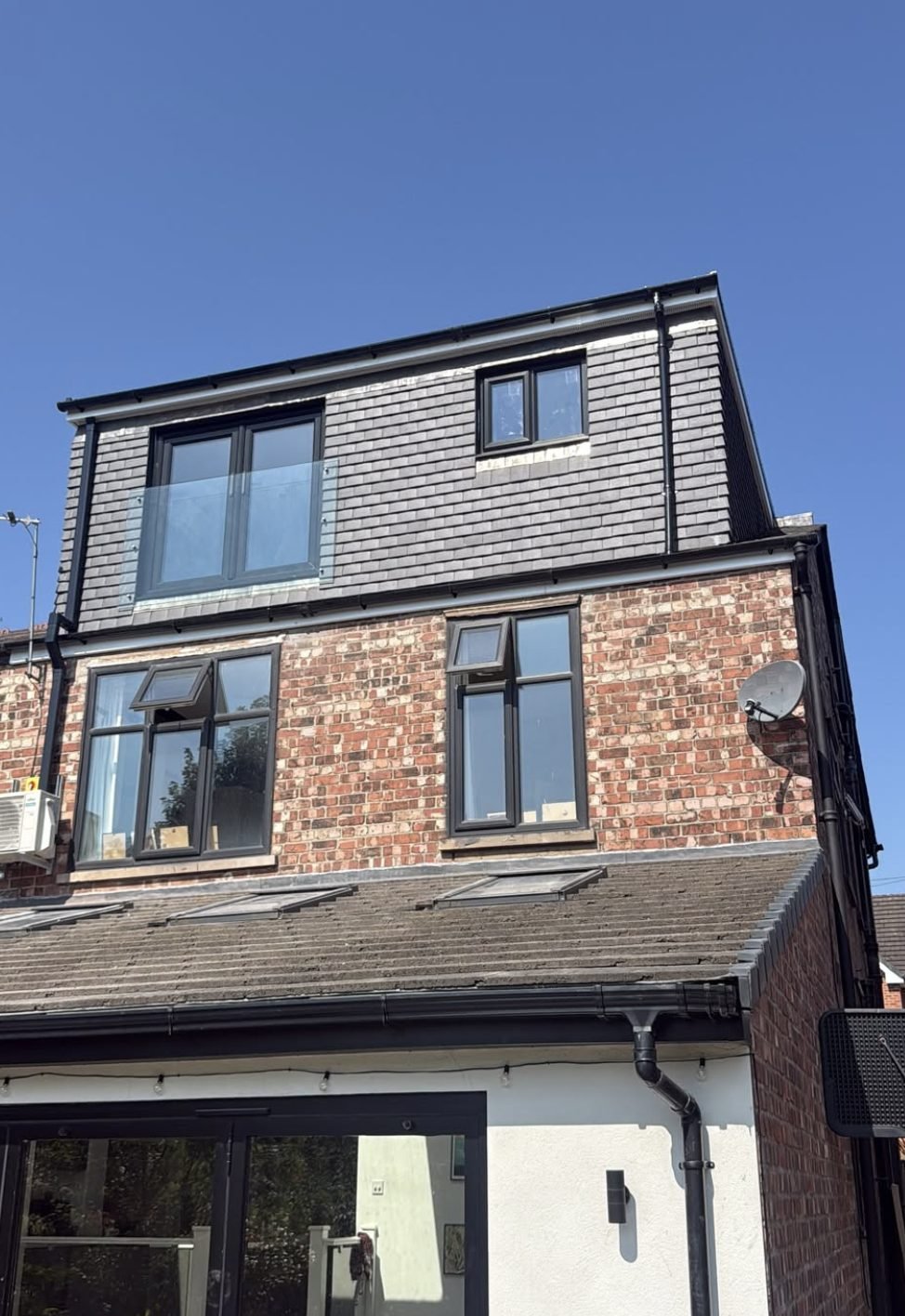 Close view of a finished tile-hung rear dormer with black windows and frameless glass Juliet balcony